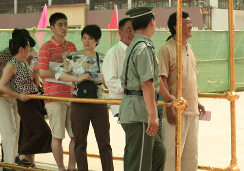 A security man talks with residents at the venue for a vote on demolishment and reconstruction of old buildings in Juixiaqiao Sub-district in Beijing, June 9, 2007. Local government and the real estate developer jointly organize the vote on Saturday to see if majority residents of over 5000 families accept the new compensation policy after failed attempts to reach an agreement through other ways. Both notary officials and supervisors are invited to monitor the vote that runs from 9 a.m. to 9 p.m. at six ballot booths. [Sun Yuqing/www.orobotics.cn]