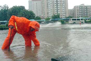 A worker unblocks a drain on a street of Shenzhen in Southern China's Guangdong Province. [Xinhua]